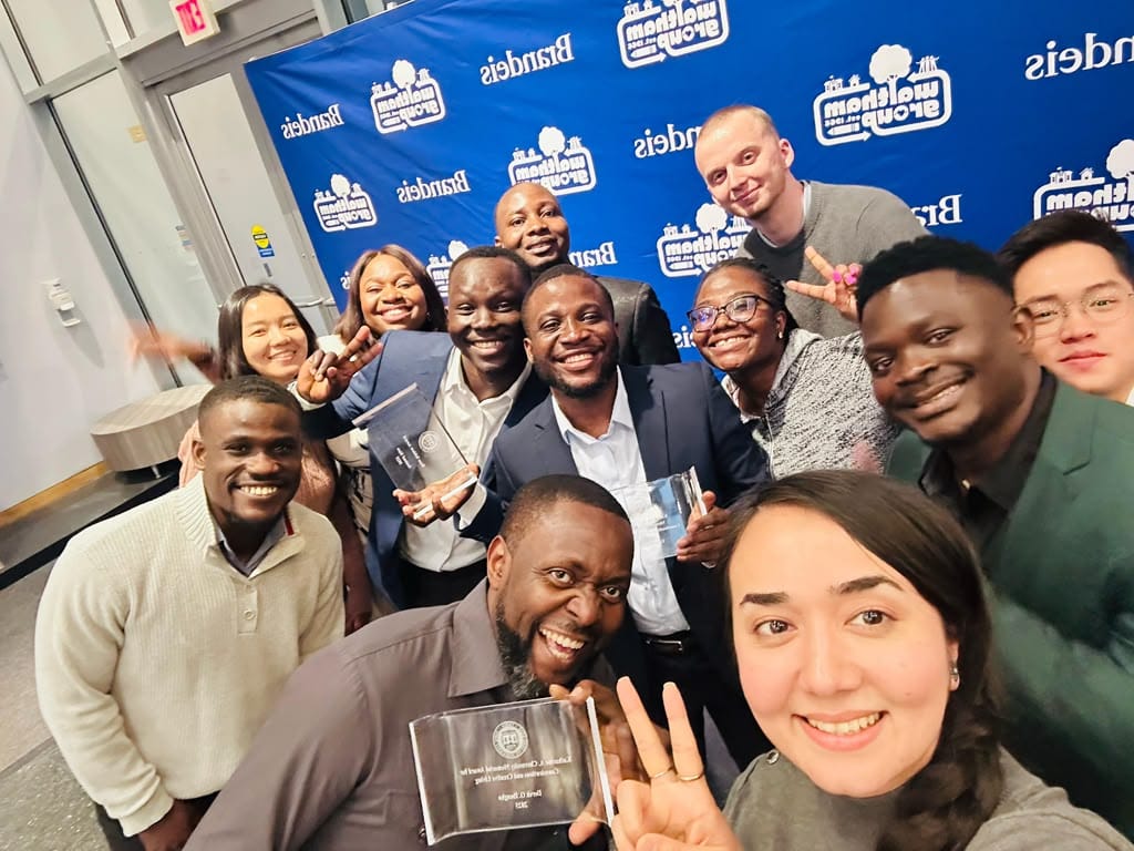 A group of students and staff celebrating together, holding glass awards at an evening ceremony