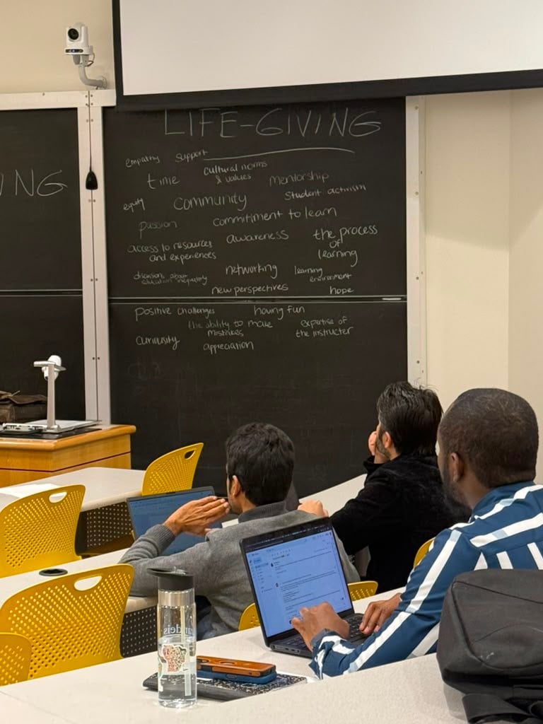Graduate students working on laptops in front of a chalkboard