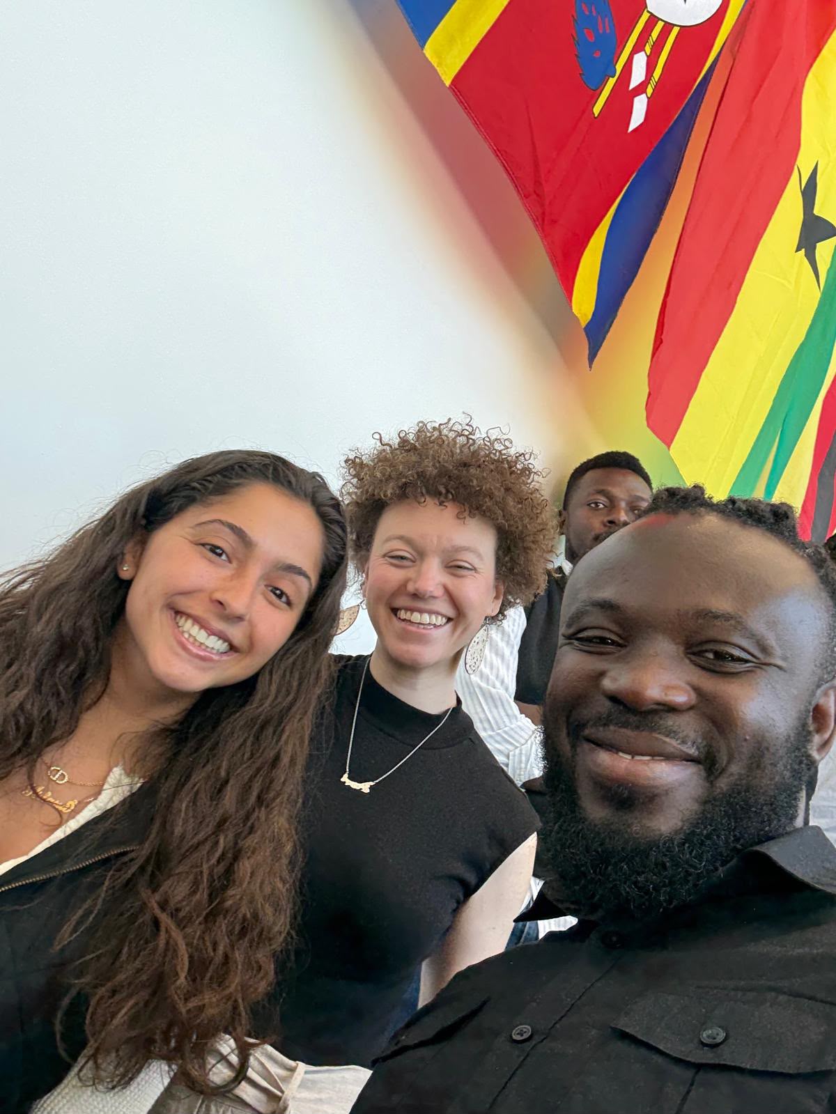 Terrick and friends smiling beneath flags