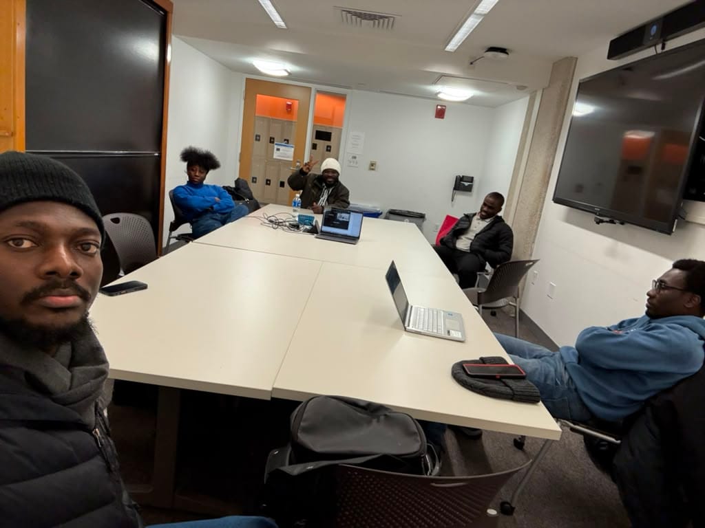 Students gathered around a table with laptops during an evening study session