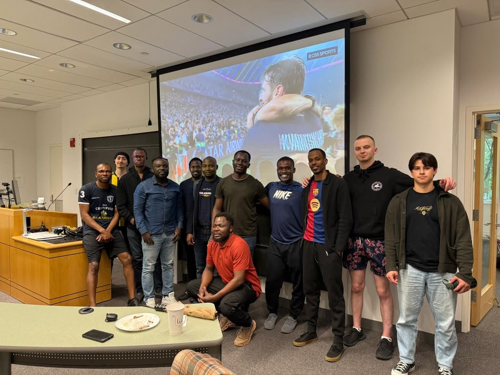 A group posing in front of a projector screen during a football watch party